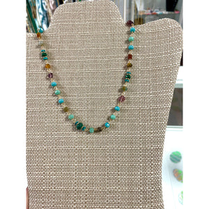 shows beads in shades of blue, green and red on a gold chain