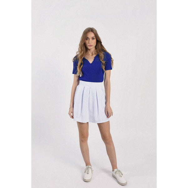 full body view showing the cobalt blue polo paired with a white skirt